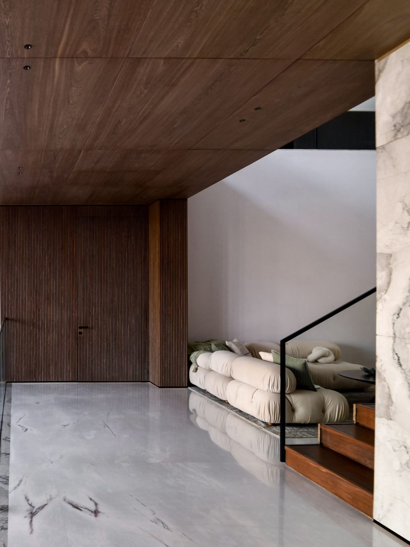 Entrée d'une villa contemporaine avec habillage mural en bois à tasseaux et marbre