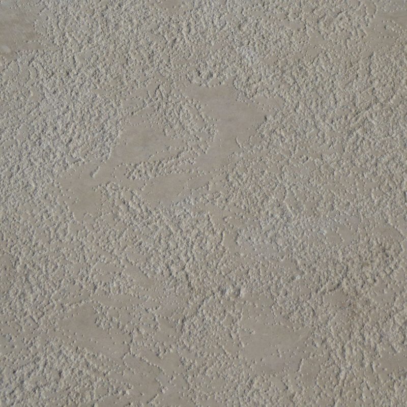 Texture de l'enduit beige révélée par la lumière rasante